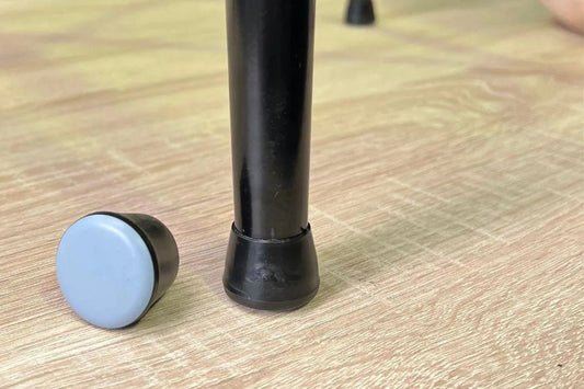 Gecko chair glides fitted to a black chair leg and shown separately with the smooth base exposed on timber flooring.