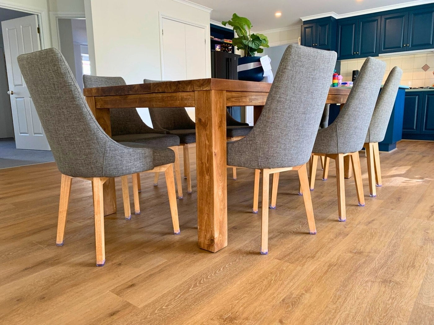 Dining table surrounded by chairs fitted with Chair Caps on a timber floor